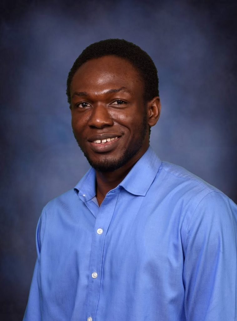 Damilola_Raiyemo A smiling young black man in a blue shirt and a blue background